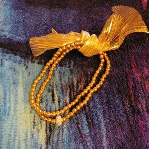 HP Golden bracelet with a small sparkly silver donut and a golden ribbon bow